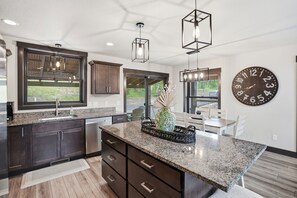 A modern kitchen with dark cabinets, granite countertops, and pendant lighting. - Pet friendly Embers Ultimate duplex, hot tub, wifi, paved roads, pool access (Lead)