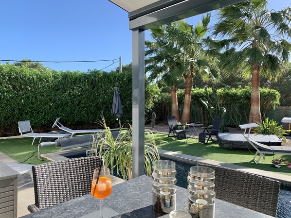 A poolside area with lounge chairs, a glass of orange drink, and a small pool.