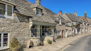 A stone building with a shop window displaying various items. - Lodge 1 (Wareham)