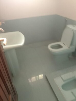 Ein kleines, kompaktes Badezimmer mit Toilette, Waschbecken und Spiegel.