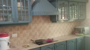 A kitchen with teal cabinets, a tiled backsplash, and a central range hood. - Impeccable 4-bed Villa in Mirpur Azad Khasmir (Mirpur)
