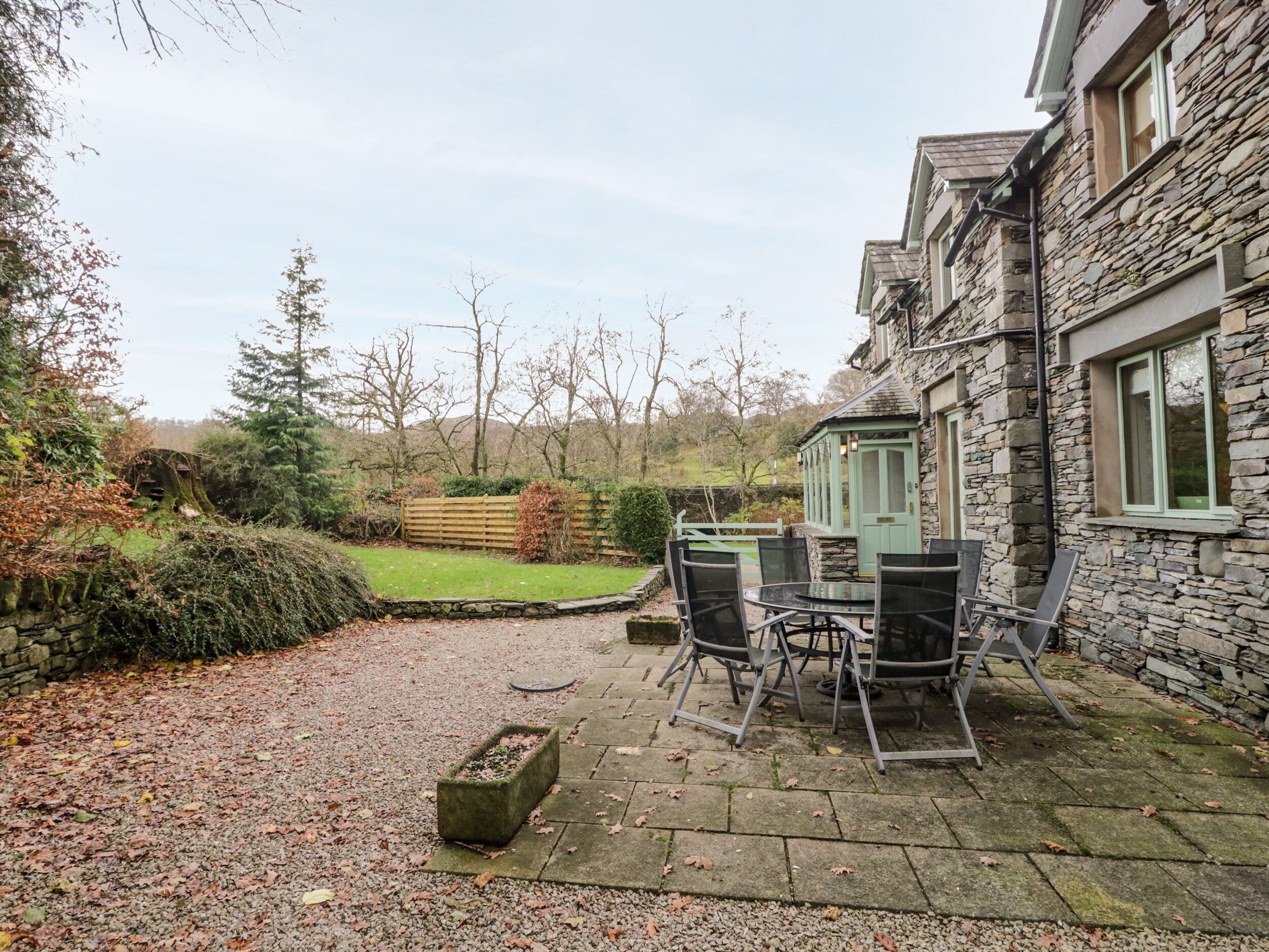 A stone house with a patio, outdoor seating, and a view of the surrounding landscape.