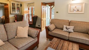 A cozy living room with two sofas, a wooden coffee table, and a lamp. - Scandale Bridge Cottage (Ambleside)
