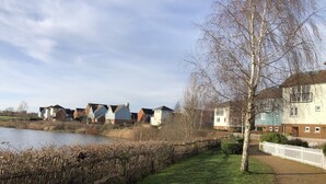 A riverside residential area with houses, a grassy path, and a white fence. - Beautiful 1-bed Apartment in Redhill (Redhill)