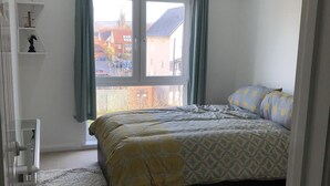 A bedroom with a bed, a window, a chair, and a dresser. - Beautiful 1-bed Apartment in Redhill (Redhill)