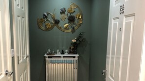 A hallway with a radiator, a decorative wall piece, and a door with a handle. - Beautiful 1-bed Apartment in Redhill (Redhill)