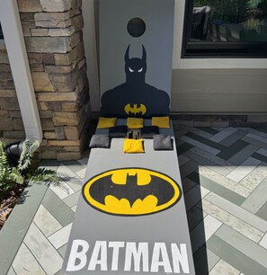 A Batman-themed bench with cushions and a logo, set against a stone wall and a window. - Waterfront 5BD/5BA Private Dock & 9P-Hottub (Six Mile)