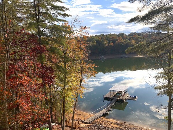 Une jetée s’avançant dans un lac paisible, bordé d’arbres aux couleurs automnales.