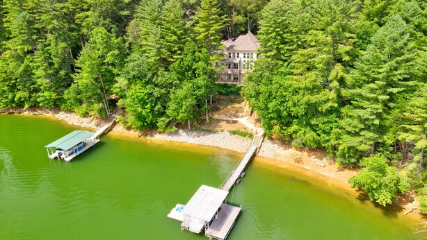Uma propriedade à beira do lago com um cais e uma casa rodeada por uma floresta densa.