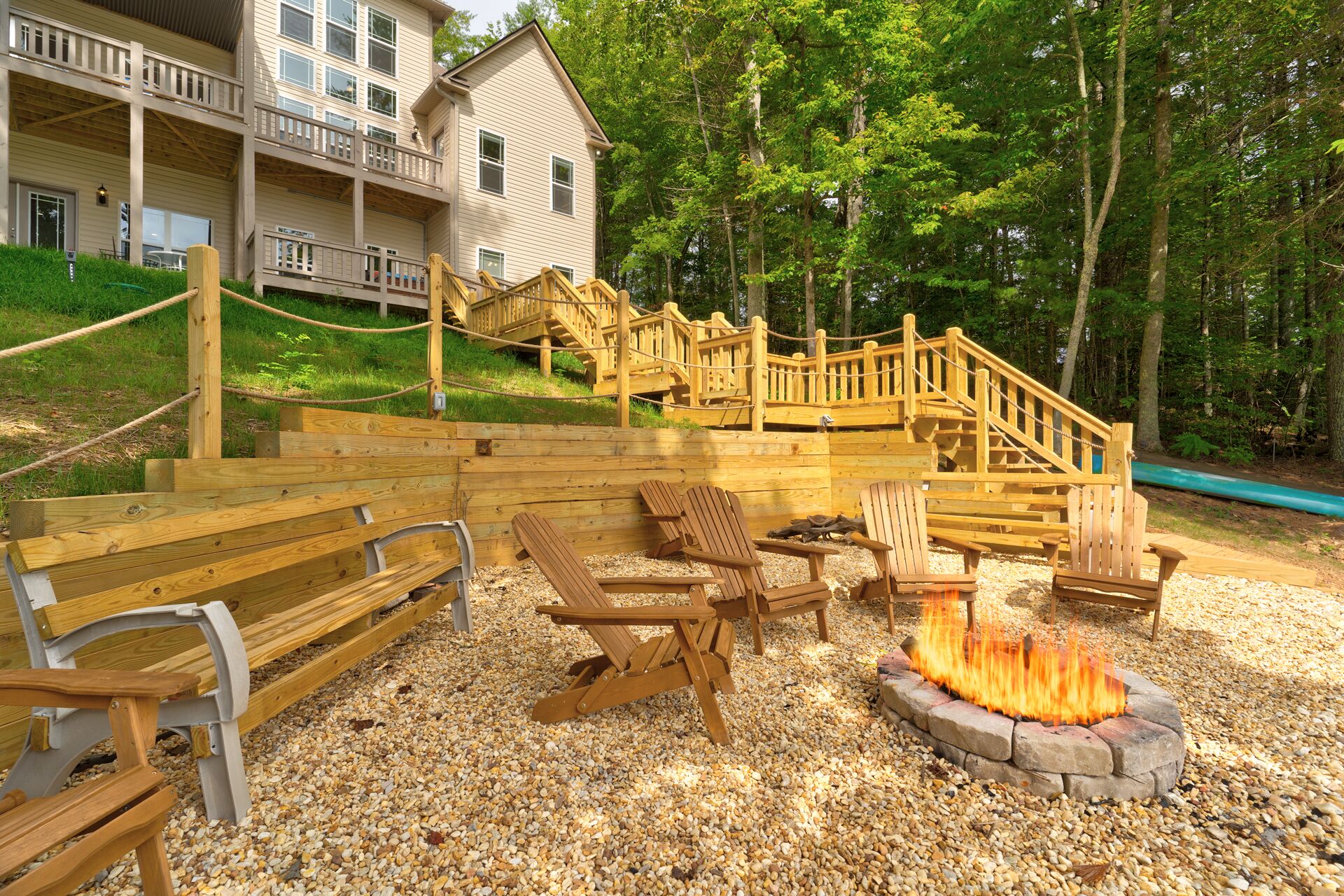 A wooden deck with outdoor seating, a fire pit, and a staircase leading to a building.