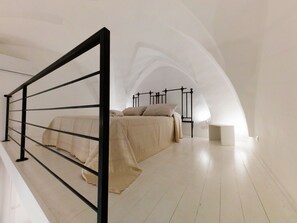 Makuuhuone, jossa on sänky, yöpöytä ja valkoinen katto.