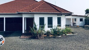 Una moderna casa a due piani con tetto in tegole rosse, facciata bianca e vialetto in ghiaia.