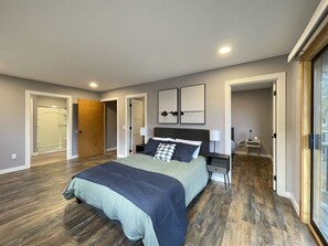 A modern bedroom with a large bed, bedside tables, and a walk-in closet.