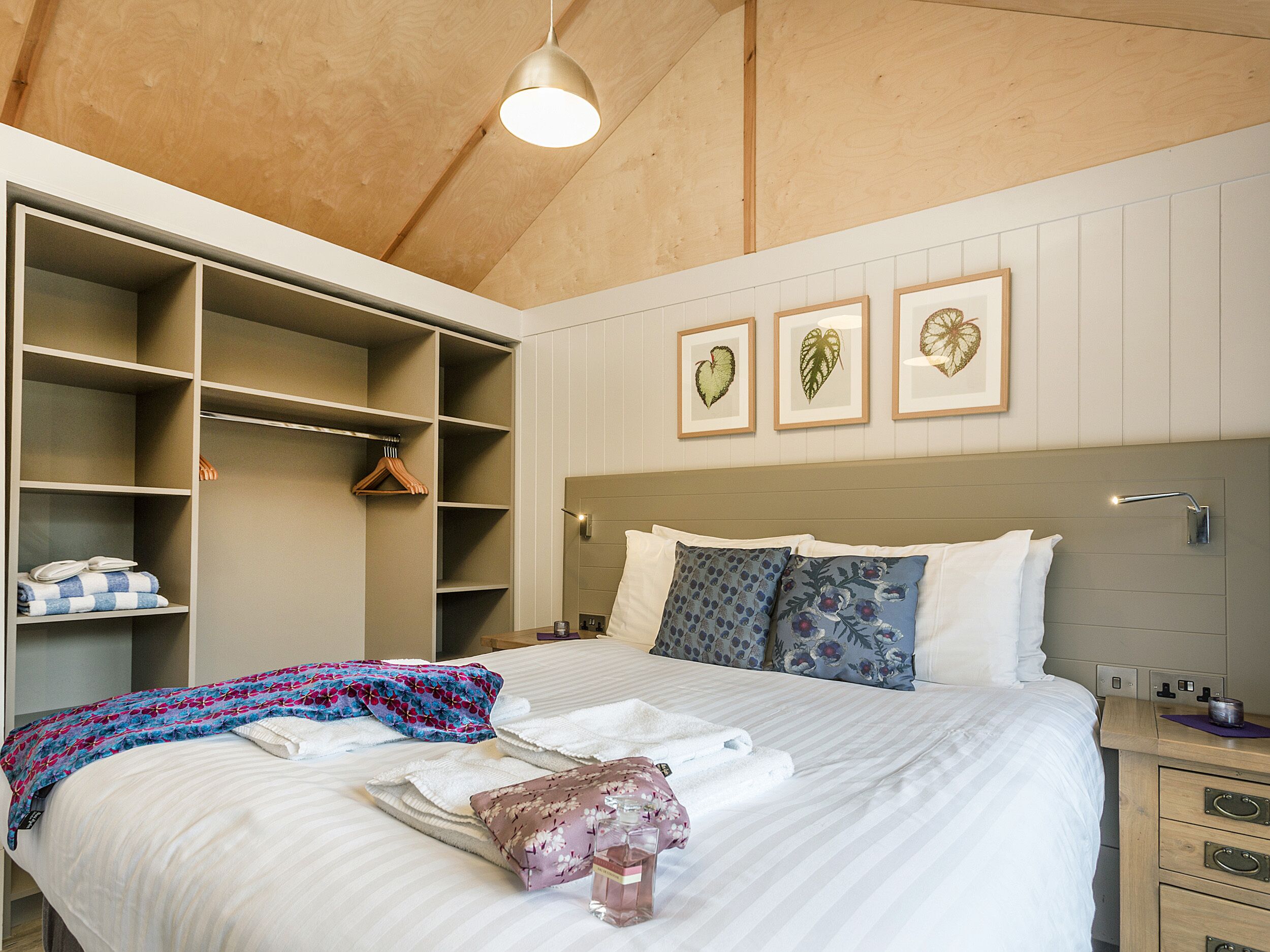 A bedroom with a large bed, a walk-in closet, and a headboard with wall-mounted lights.