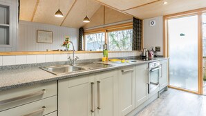A modern kitchen with a granite countertop, stainless steel sink, and wooden cabinets. - Lodge 10 (Wareham)