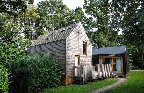 A wooden cabin with a sloped roof, a small porch, and a fenced yard. - Lodge 6 (Wareham)