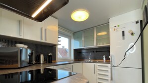 A modern kitchen with a black induction cooktop, stainless steel appliances, and white cabinetry. - Flat With 2BR and Terrace Between Restaurants (Stavanger)