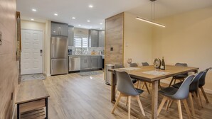 A modern kitchen with stainless steel appliances, a dining area with a wooden table and chairs, and a minimalist design. - Ski on/off home in Camelback (Tannersville)