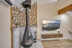 A modern living room with a stone wall, a fireplace, a TV, and a wooden bench.