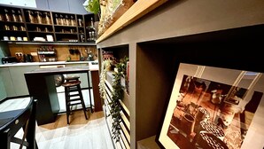 Una cocina moderna con barra, estantes con frascos y botellas, y un cuadro en la pared.