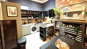 Una cocina moderna con lavadora integrada, un comedor con mesa y sillas, y un espejo decorativo en la pared.