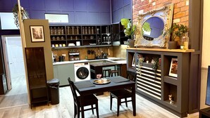 Una cocina moderna con lavadora integrada, un comedor con mesa y sillas, y una pared de ladrillo decorativa.