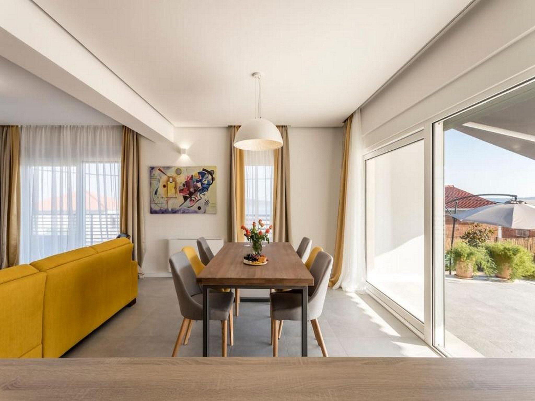 Un espace repas moderne avec une table en bois, des chaises et un canapé jaune.