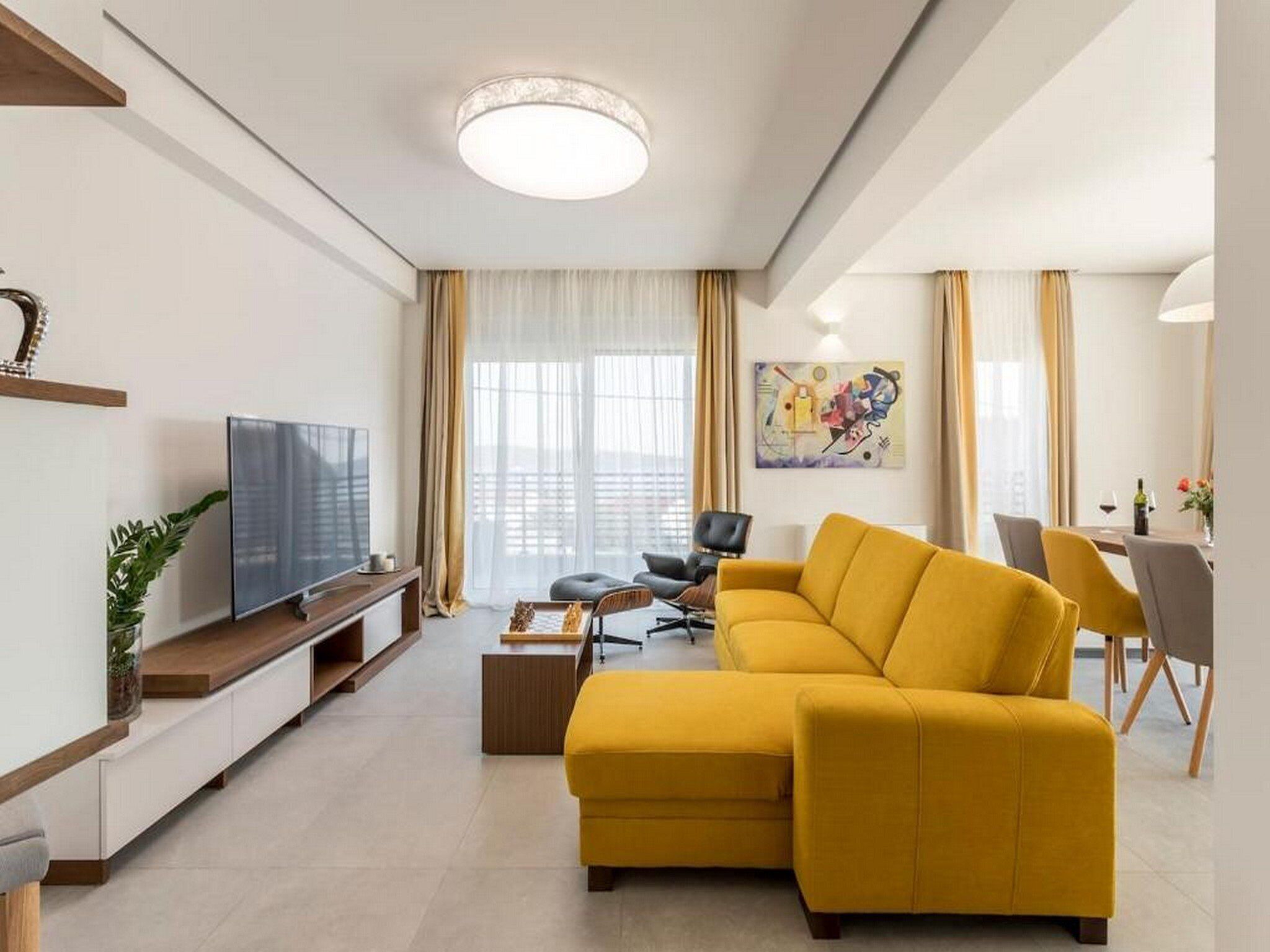 Un salon moderne avec un canapé, un téléviseur et un coin repas.