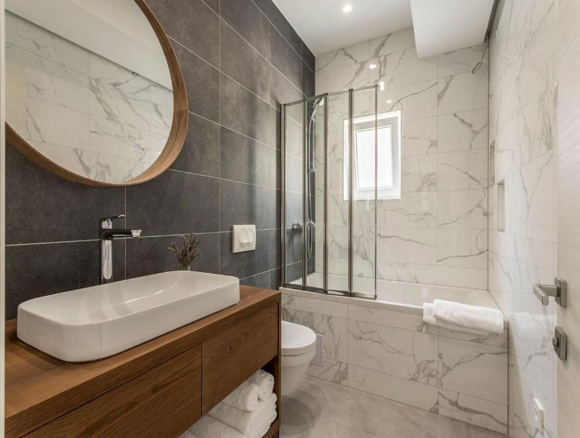 A modern bathroom with a large oval sink, a glass-enclosed shower, and a toilet.