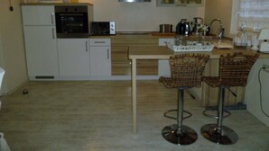 Een compacte keuken met een centraal eiland, twee barkrukken en een magnetron.