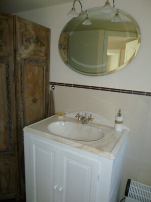 Bathroom features a classic sink, round mirror, and wooden cabinet with ornate details.