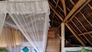 A room with a bed under a canopy, a sofa, and a decorative wall.