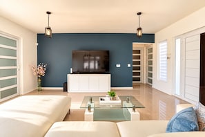 A modern living room with a flat-screen TV, a glass coffee table, and a sofa. - New-Modern Villa Island Escape, 10 Minute Drive to Beaches (Oranjestad)