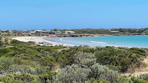 Zona costera con playa, edificios y abundante vegetación.