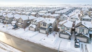 A residential area with houses covered in snow, a road, and a clear sky. - Blue Moon | Playground | Backyard | Pet Friendly (Calgary)