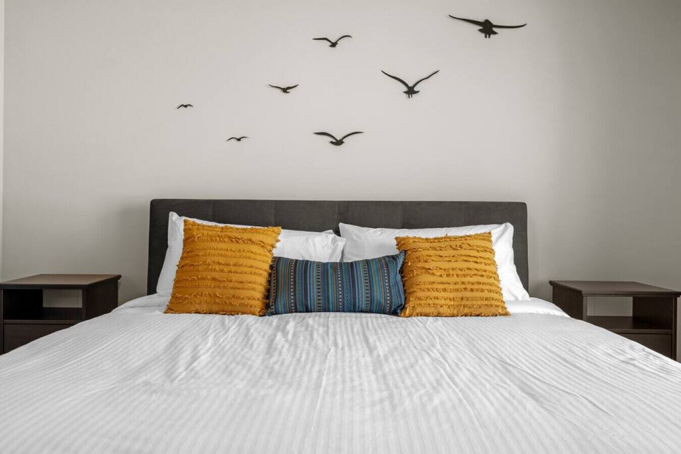 A bedroom with a bed, two nightstands, and a wall with bird silhouettes.