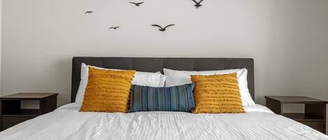 A bedroom with a bed, two nightstands, and a wall with bird silhouettes.