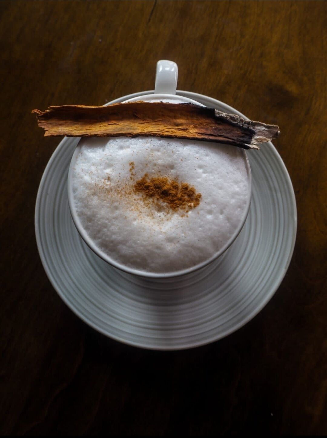 A cup of coffee with a piece of dried fruit on top, placed on a plate.