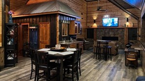 A rustic interior with a wooden dining area, kitchen, and stone fireplace. - Cozy Cabin W/ 2 King Suites, Pet Friendly, Hot tub (Broken Bow)