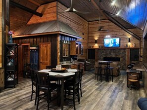 Un'atmosfera rustica con zona pranzo in legno, cucina e camino in pietra.