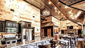 A rustic kitchen with stone countertops, wooden cabinets, and a stone fireplace. - Cozy Cabin W/ 2 King Suites, Pet Friendly, Hot tub (Broken Bow)