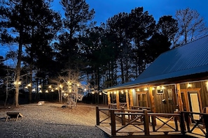 Un edificio rustico in legno con una zona salotto esterna coperta e luci decorative.
