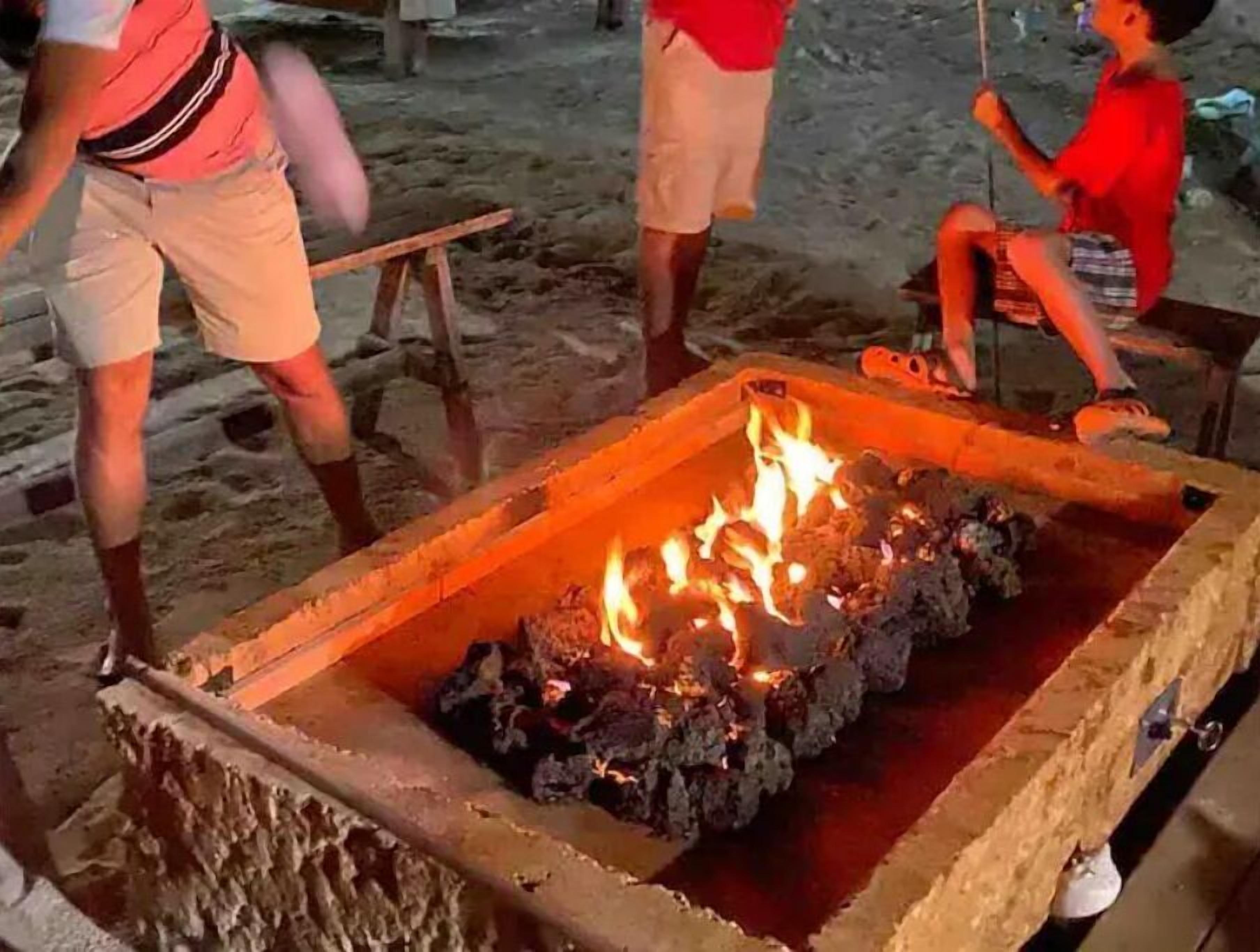 A fire pit with logs, surrounded by a stone structure.