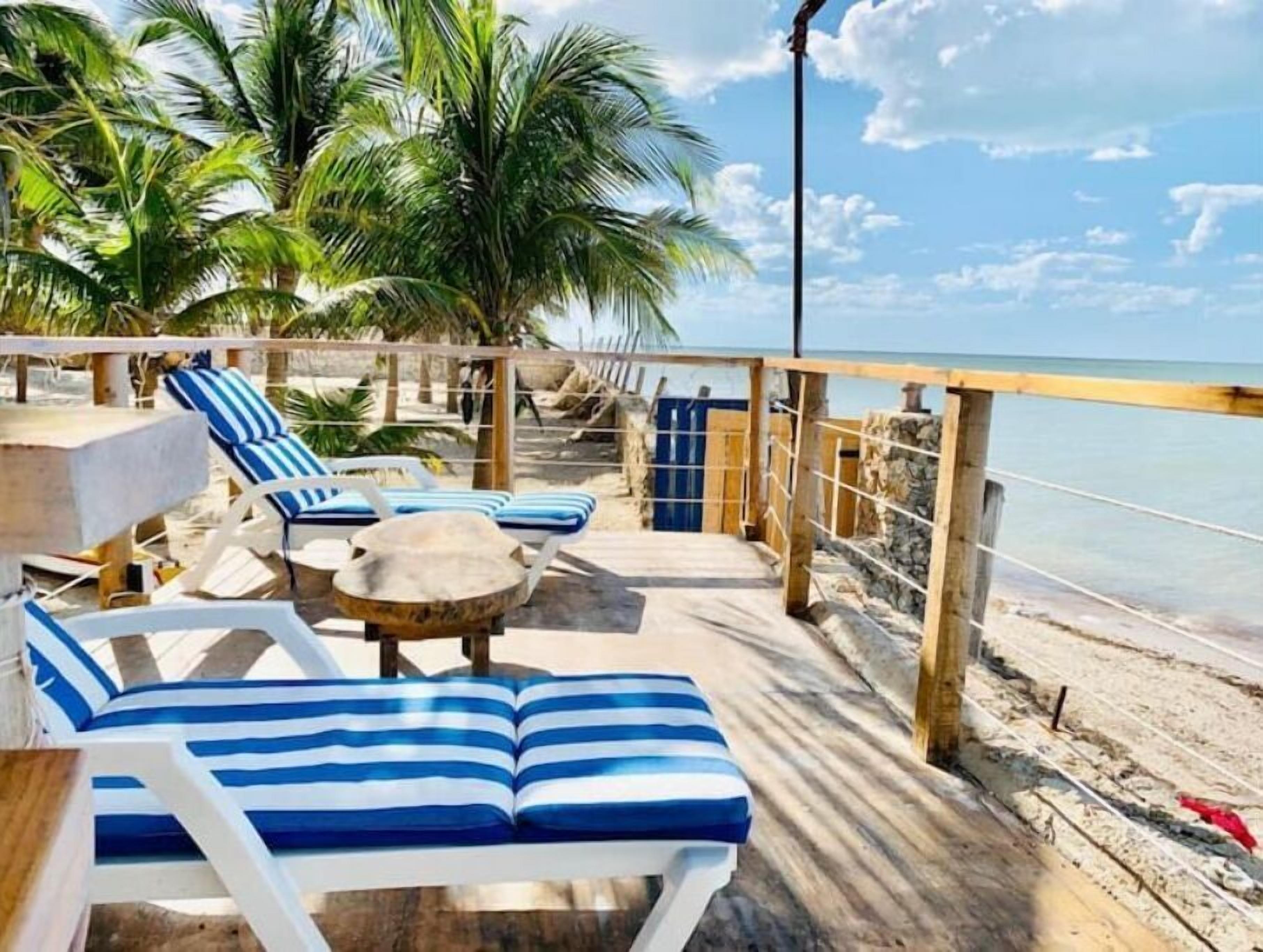 Eine Strandterrasse mit Liegestühlen und einem Tisch mit Blick aufs Meer.