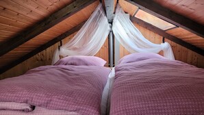 Una habitación con dos camas, cada una cubierta con una manta morada. Un dosel blanco está colgado sobre las camas.