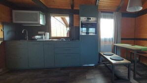 Cocina compacta con horno integrado, un lavamanos y un pequeño comedor con taburetes.