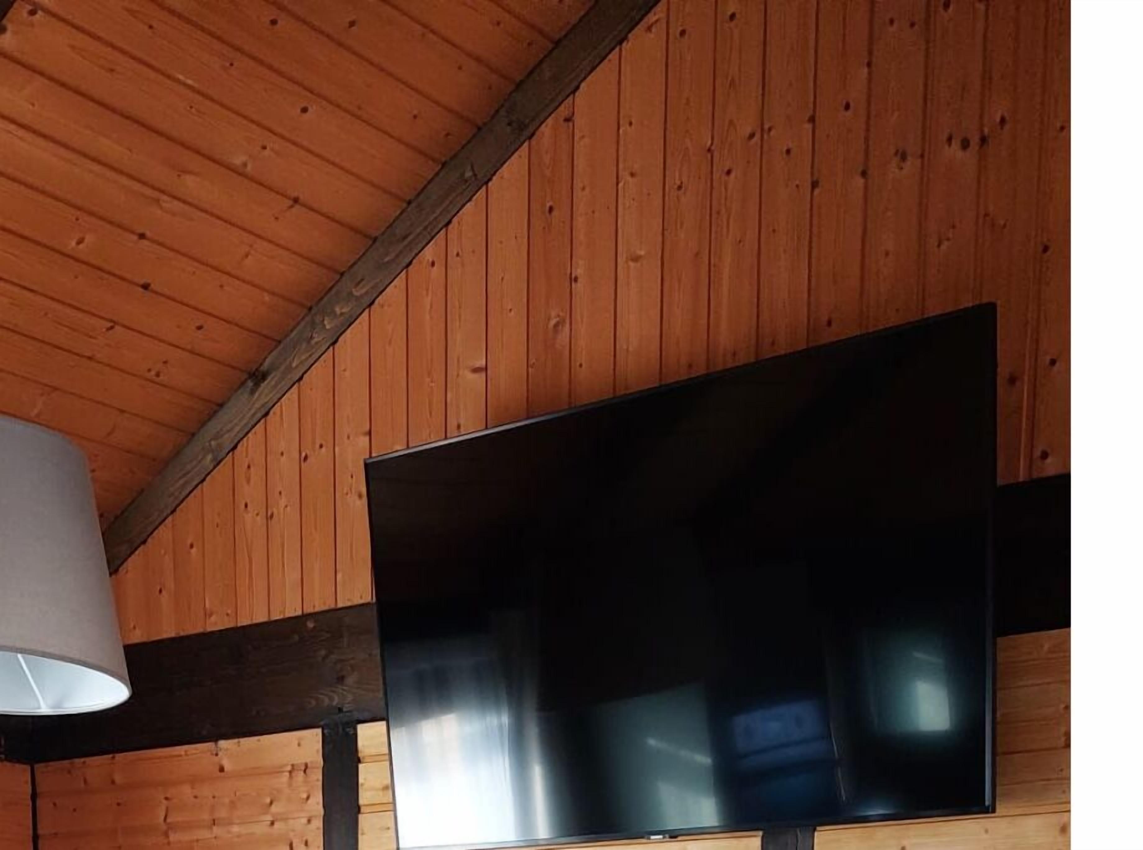 A room with wooden walls and a large flat-screen TV mounted on the wall.