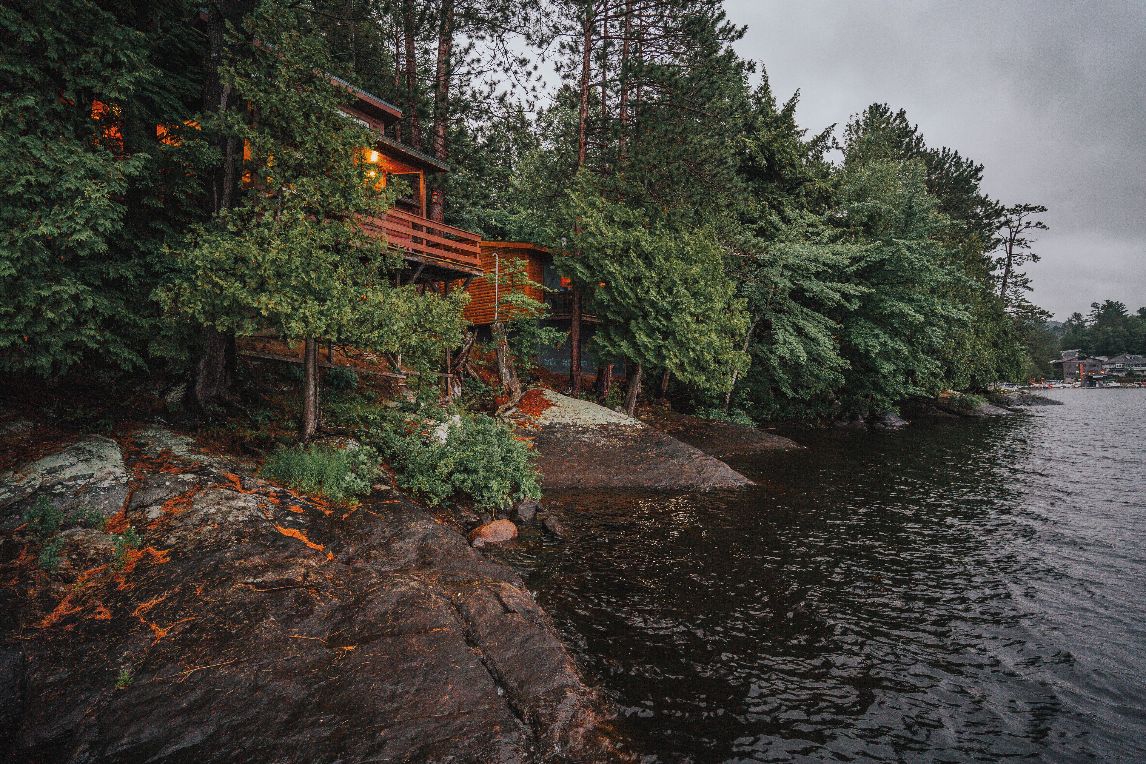 A cabin by a lake surrounded by dense forest.