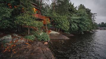 A cabin by a lake surrounded by dense forest.