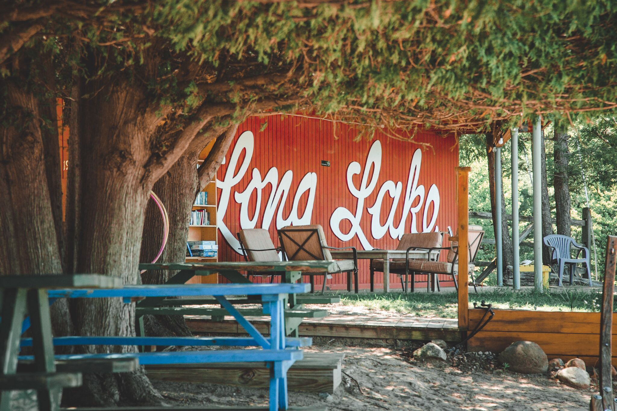 A rustic outdoor seating area with a red wall labeled "Luna Lake," wooden benches, and a picnic table.